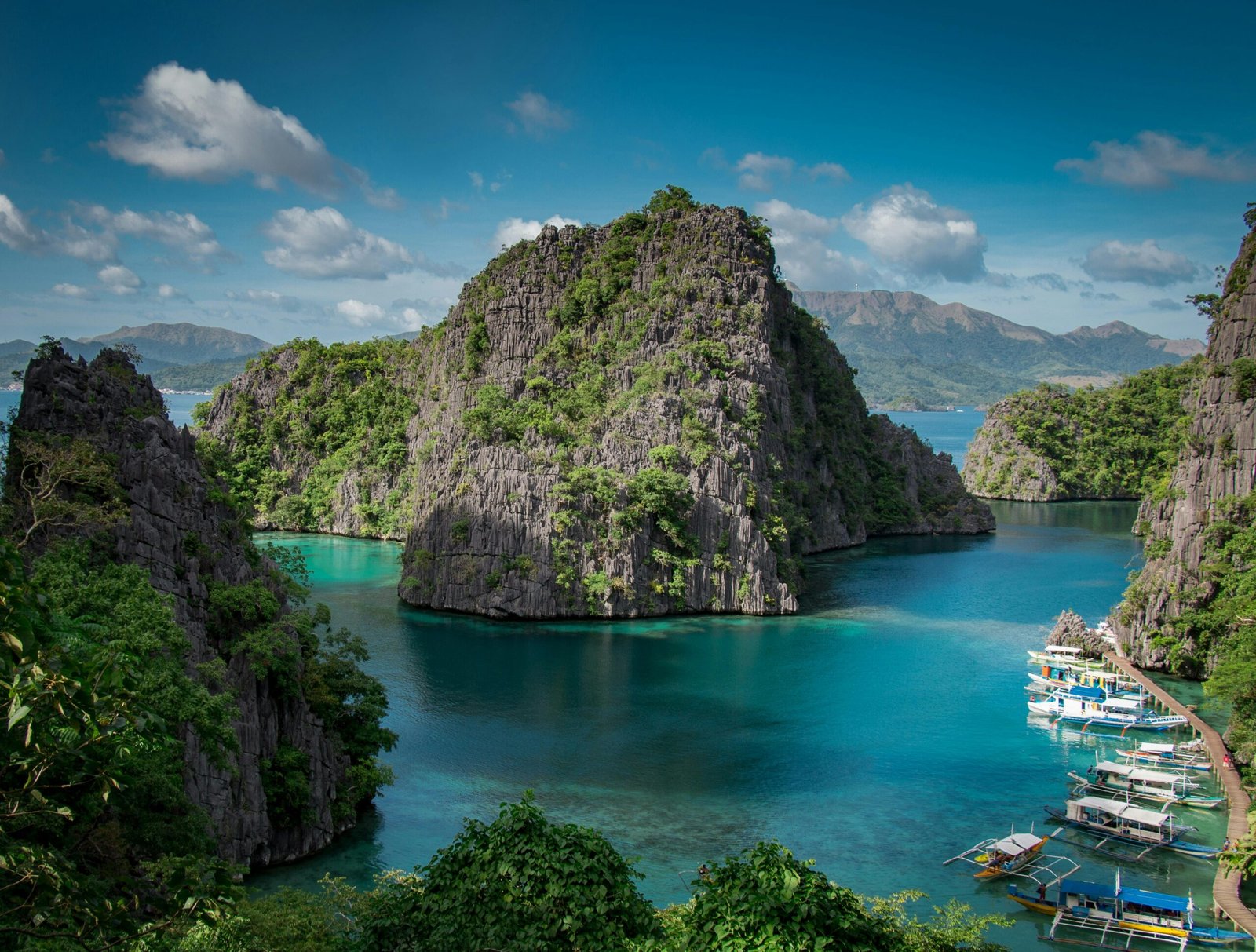 Stunning view of Coron Island's turquoise waters with rock formations and boats.