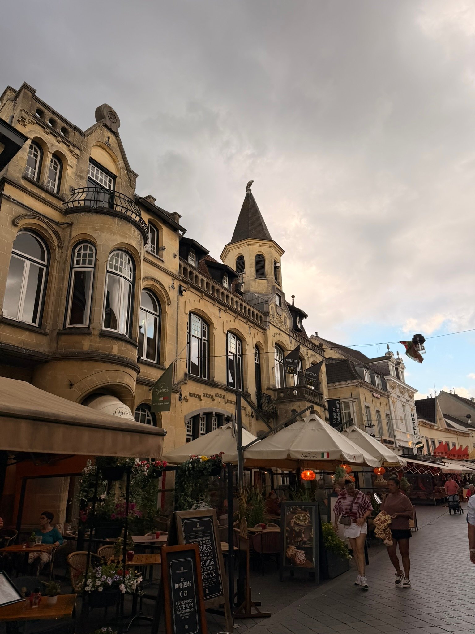 Ornate marl-stone buildings and terrace umbrellas on the main street in Valkenburg, Netherlands