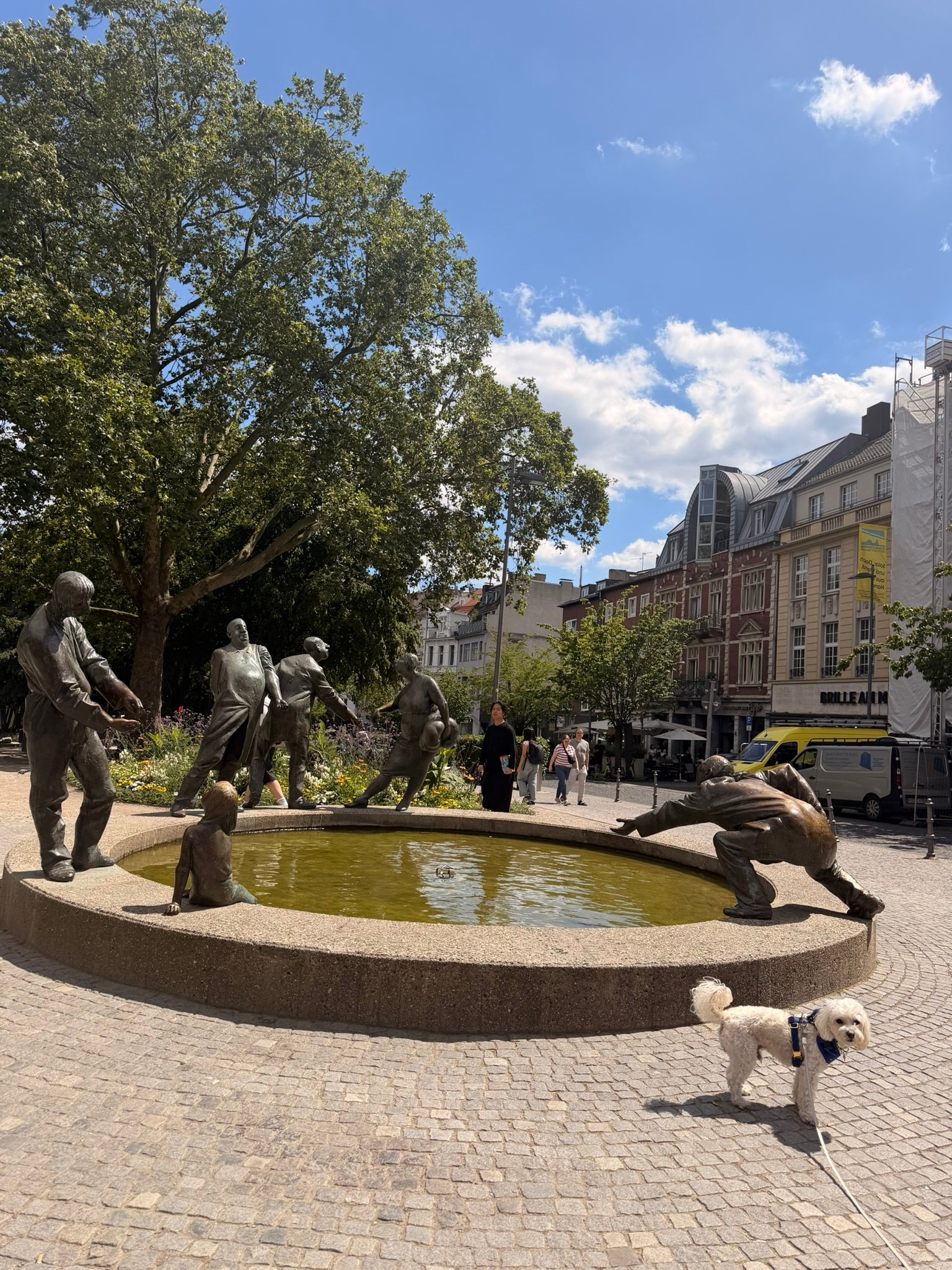 Cookie the Maltipoo in front of the Kreislauf des Geldes fountain in Aachen